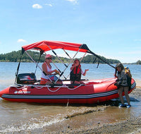 An Inflatable boat, this is a large Saturn inflatable motor boat with motor, boat canopy, oars, and life vest all on a lakeshore. 